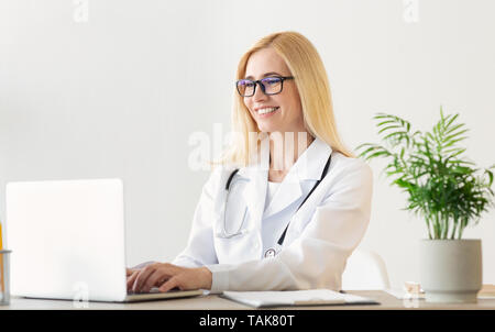 Happy Female Doctor Working On Laptop Computer Stock Photo