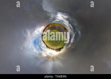 Little planet transformation of spherical panorama 360 degrees. Spherical abstract aerial view in field in nice evening with awesome beautiful clouds. Stock Photo