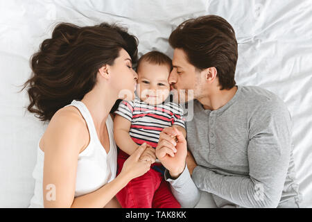 Mother and father kissing their adorable baby Stock Photo