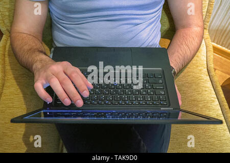 Man works with a laptop touching the screen with his fingers Stock Photo