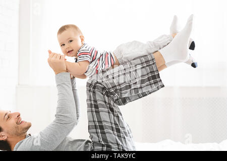 Happy father playing with adorable baby in bedroom Stock Photo