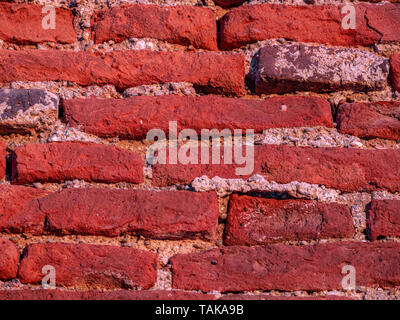 Old red grunge brick wall background during sunset Stock Photo