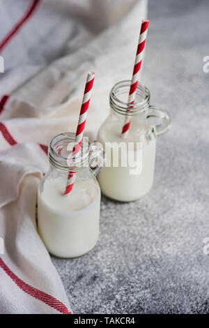 Milk in vintage bottles with stripped red and white straws on grey concrete  table with copyspace Stock Photo