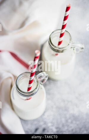 Milk in vintage bottles with stripped red and white straws on grey concrete  table with copyspace Stock Photo