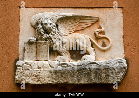 Carved stone winged lion - the symbol of Venice - on the exterior wall of an historic building in the centre of the city. Stock Photo