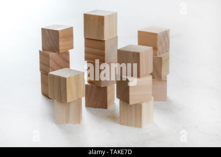 Stacks of wooden toy cubes creating small towers on white board Stock Photo