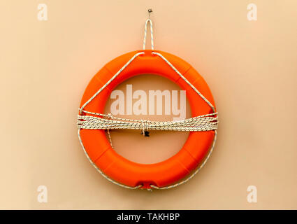 Orange life buoy with nautical ropes hanging on the wall Stock Photo