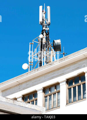 Cell phone telecommunications antennas and repeaters on building against clear blue sky Stock Photo