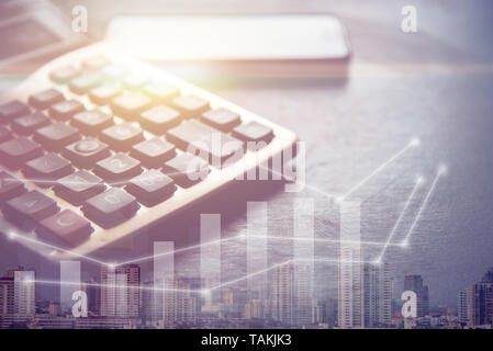 dark tone of calculator and smart phone, success graph and building in big city, business concept Stock Photo
