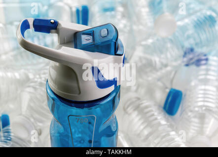 Close up of a reusable water bottle with many plastic single use disposable bottles in the background with a shallow depth of field Stock Photo