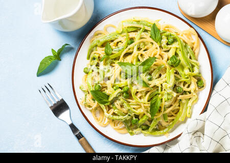 Pasta spaghetti with zucchini, green peas and cream sauce. Vegetarian vegetable pasta. Zucchini noodles. Top view copy space. Stock Photo