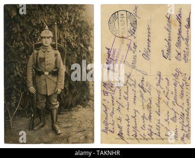 German historical photo: a handsome young soldier in full gear in military uniform with weapons, a rifle with bayonet knife, entrenching shovel, 1916 Stock Photo