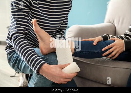 Woman with sprain to her ankle applying bandage Stock ...