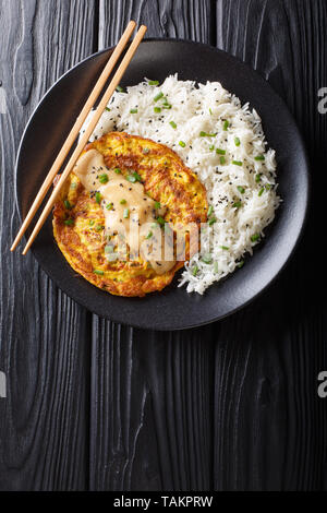 Crispy fluffy egg foo young filled with crisp veggies and aromatic green onion and served with a rice close-up on a plate. Vertical top view from abov Stock Photo