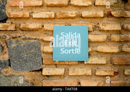 Trilingual exit sign in three languages (Spanish, English, and French) on an old brick wall in Toledo, Castilla-La Mancha, Spain. Stock Photo