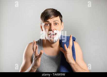 Shocked man having half of his face shaved against grey background Stock Photo