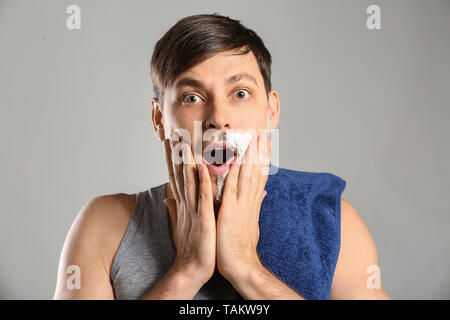 Shocked man having half of his face shaved against grey background Stock Photo