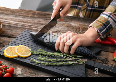 Woman preparing tasty mackerel fish on table in kitchen Stock Photo