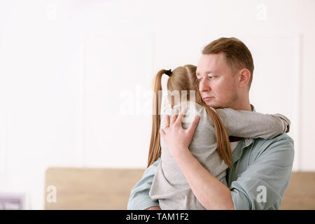 Sad divorced man hugging his little daughter at home Stock Photo