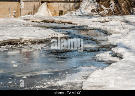 Spring thawed patch in the ice of the river. Frozen ice and snow by the river side. Natural background. Stock Photo