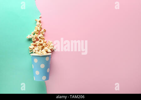 Overturned paper cup of tasty popcorn on color background Stock Photo