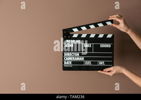 Female hands with cinema clapperboard on color background Stock Photo