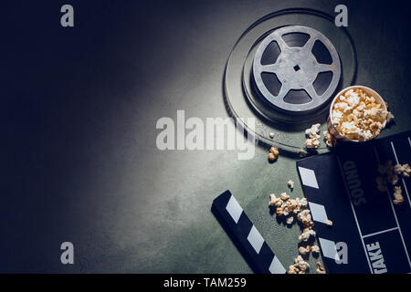 Composition with cinema clapperboard, film reel and popcorn on dark background Stock Photo