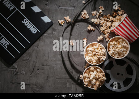 Composition with popcorn, cinema clapperboard and film on dark background Stock Photo