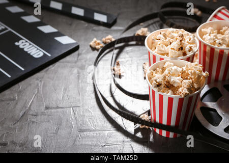Composition with popcorn, cinema clapperboard and film on dark background Stock Photo