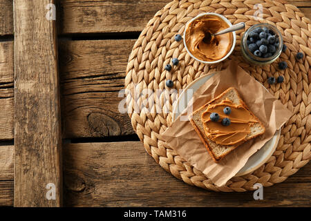 Toasted bread with tasty peanut butter and berries on wooden table Stock Photo