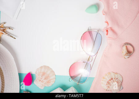 Flat lay composition with sunglasses, seashells, sunblock, pink t shirt, straw hat. Beach accessories on white light blue background. Summer, vacation Stock Photo