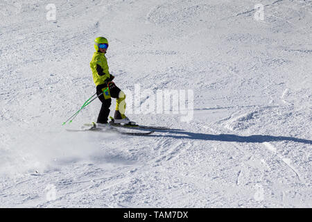 The boy stands on skis on the ski slope. Skier across the slope at the time of braking, a whirlwind of snow behind it Stock Photo