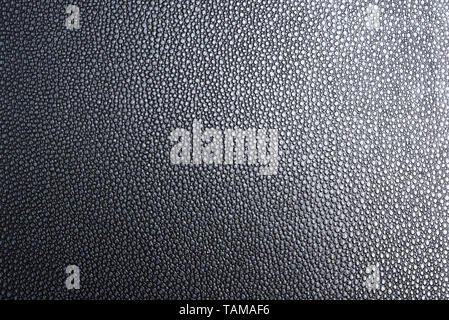 The texture of a black faux leather with clear details under a graduated lighting. Stock Photo