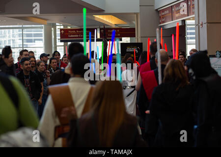 People holding up multicolored lightsabers dressed in cosplay costumes at Star Wars Celebration 2019 - Chicago, IL Stock Photo