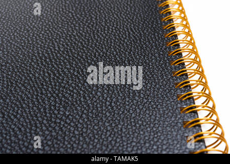 Black faux leather textured notebook cover in a yellowed metal ring binder and set on a plain white background. Stock Photo