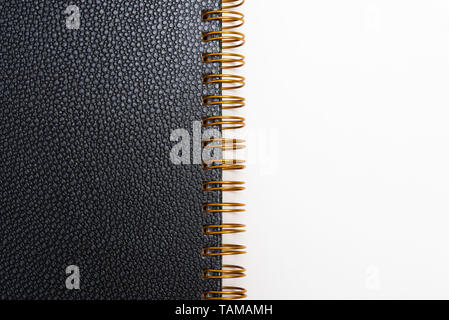 Black faux leather textured notebook cover in a yellowed metal ring binder and set on a plain white background. Stock Photo