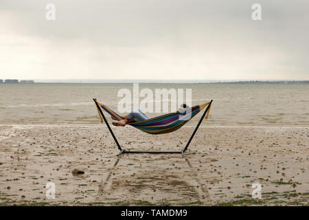 Southend on Sea, UK. 26th May, 2019. A man rests in a hammock as the tide goes out at Westcliff on Sea. Scenes in Leigh and Southend on Sea, Essex, as people get out to enjoy the long weekend. Penelope Barritt/Alamy Live News Stock Photo