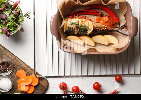 Baking dish with tasty mackerel fish and vegetables on white table Stock Photo