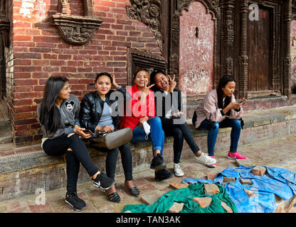 Smiling young Nepelese women sitting on the stairs in front of the Jagannath Temple, Hanumandhoka Durbar square, Kathmandu, Nepal Stock Photo