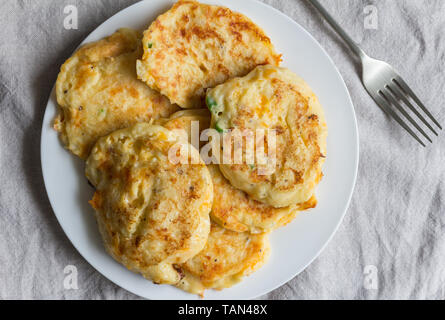 Potato cakes heaped on white plate with serving fork - top view photo Stock Photo