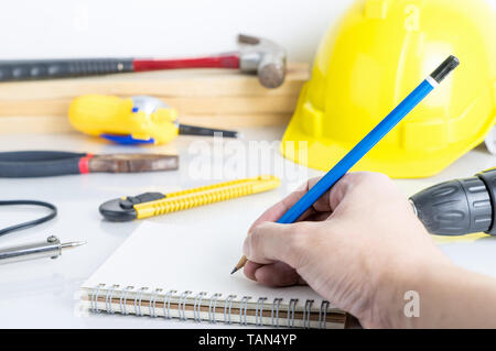 Engineer is writing on blank notebook on working desk tools Stock Photo