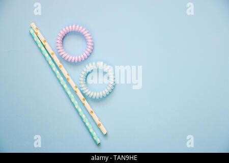 flat lay of spiral hair bands and tubes on a blue background copy space, abstract background Stock Photo