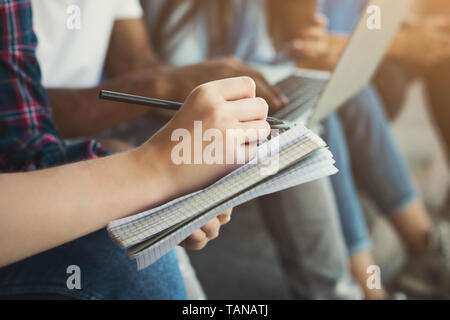 Teen girl writing notes in notebook outdoor Stock Photo