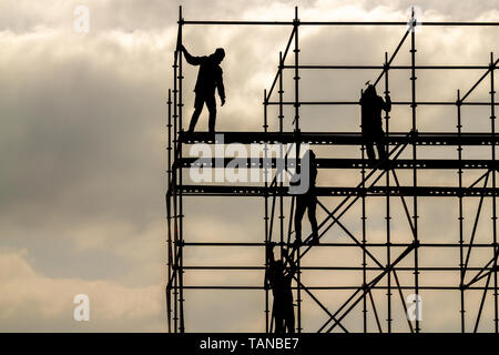 Construction workers silhouette working on iron platform sky background Stock Photo