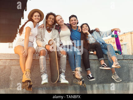 Group of active teenagers laughing together, city evening Stock Photo