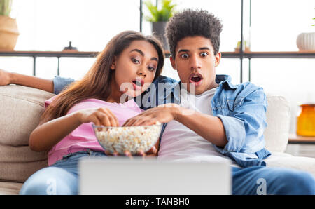 Shocked teen couple watching scary movie on laptop Stock Photo