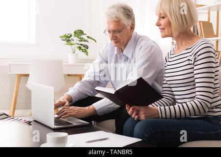 Mature Couple Checking Domestic Finances Using Laptop Stock Photo