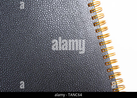 Black faux leather textured notebook cover in a yellowed metal ring binder and set on a plain white background. Stock Photo