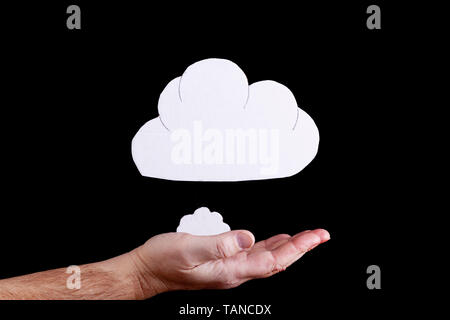 Cloud concept with cardboard cloud cutouts floating above an open hand on a black background Stock Photo
