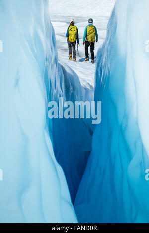 Two ice climbers walking away from a narrow crevasse. The women are ice climbing guides on the Matanuska Glacier in Alaska. Stock Photo